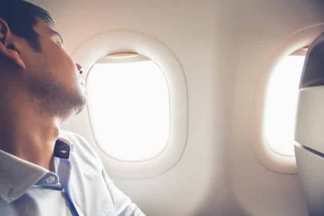 Tired passenger sleeping on the airplane at window seat