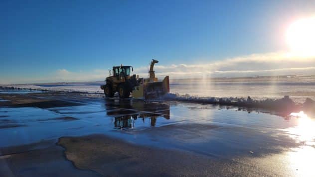 image of large snow blower on FNL airport ramp with sun in the background